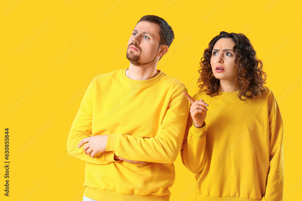 Upset young couple on yellow background