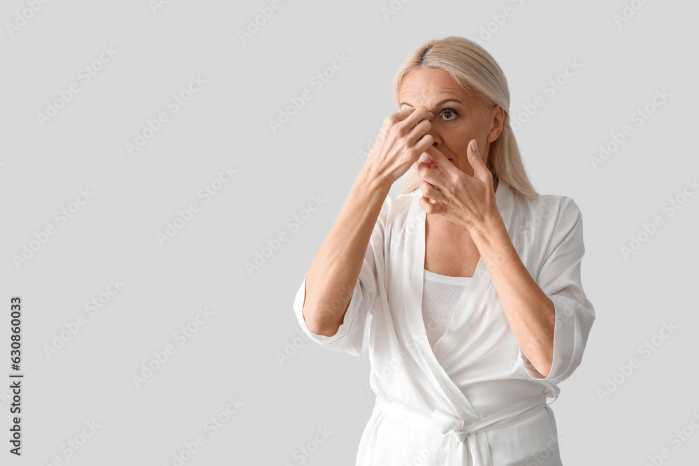 Mature woman doing face building exercise on light background