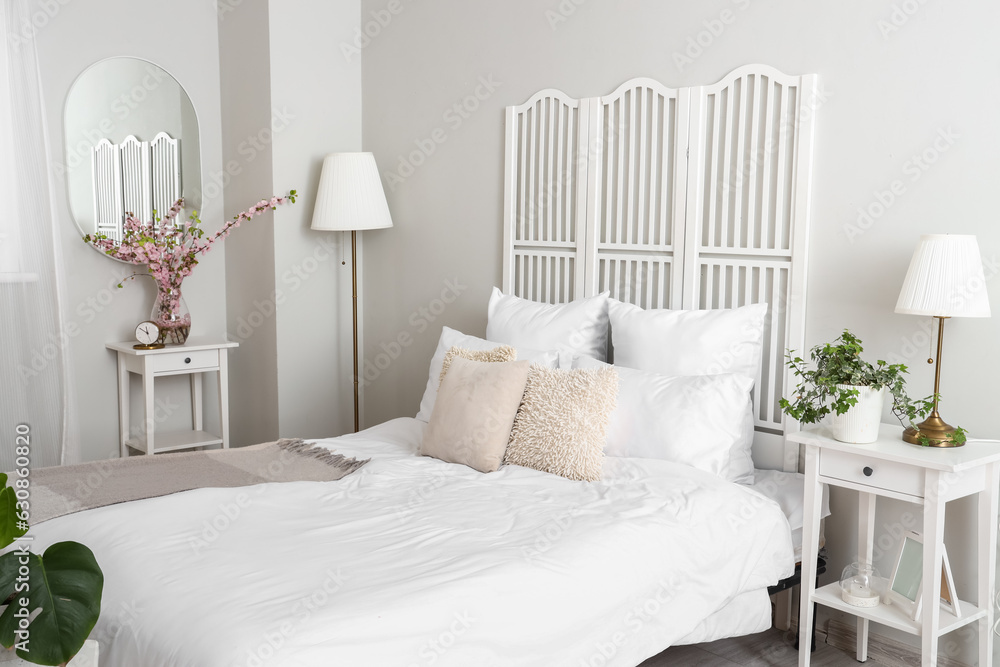 Interior of light bedroom with houseplant on bedside table