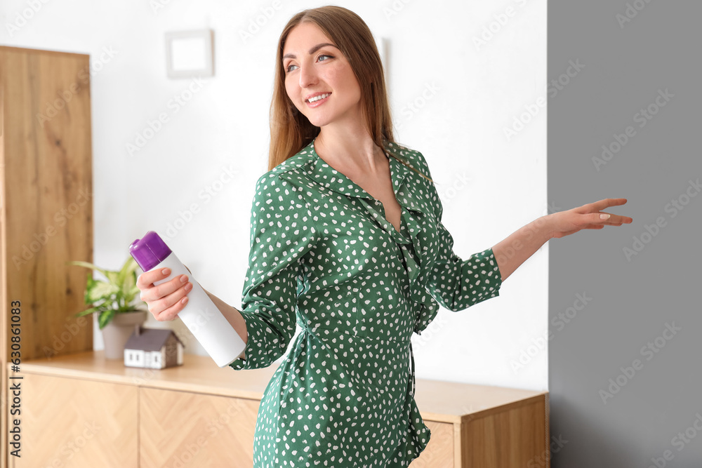 Young woman with air freshener at home