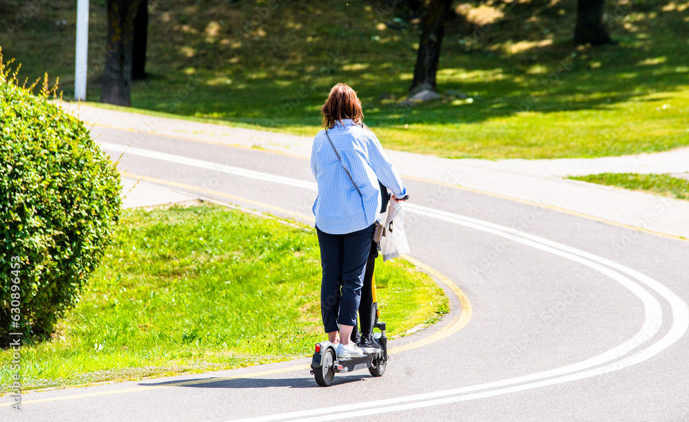 Girl rides an electric scooter in the summer Park 