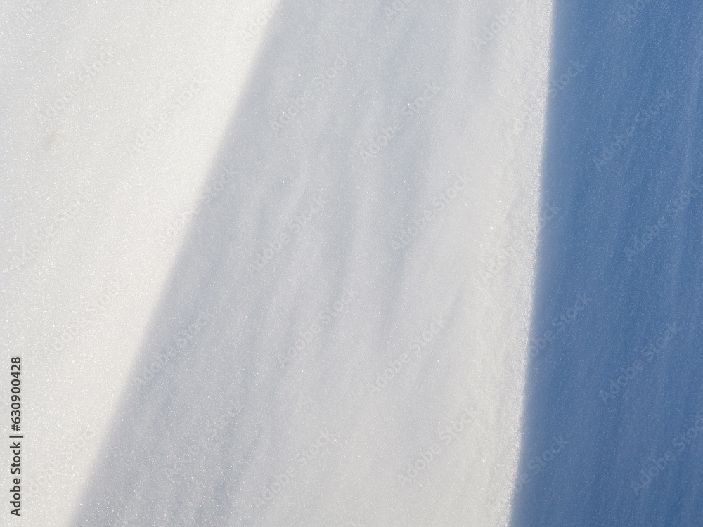 Beautiful winter background with snowy ground. Natural snow texture. Wind sculpted patterns on snow 