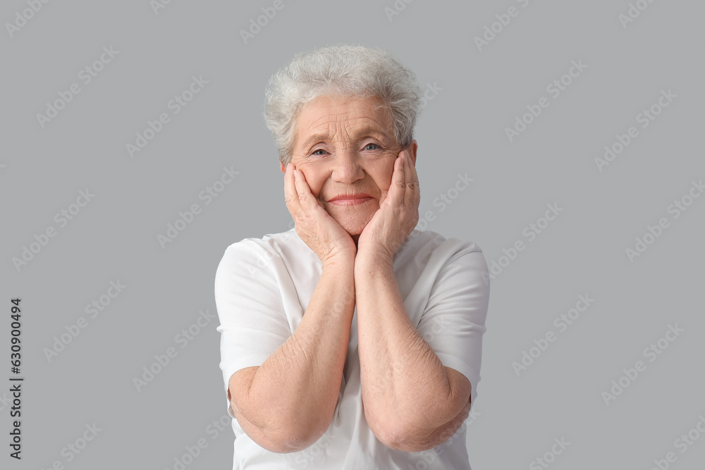 Happy senior woman on grey background