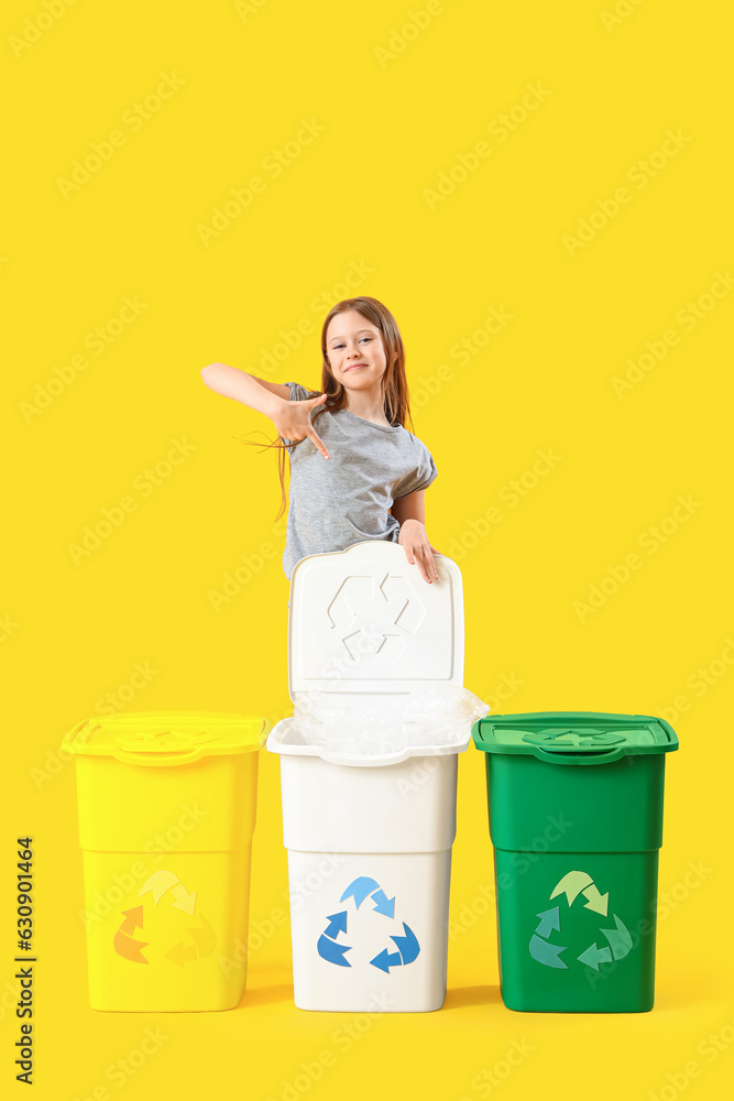 Little girl pointing at recycle trash bins on yellow background