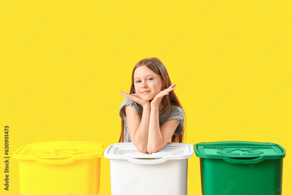 Little girl with recycle trash bins on yellow background