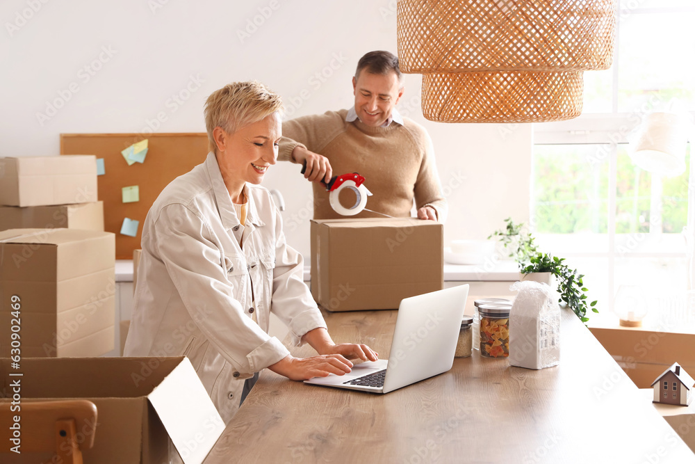 Mature couple with laptop in kitchen on moving day