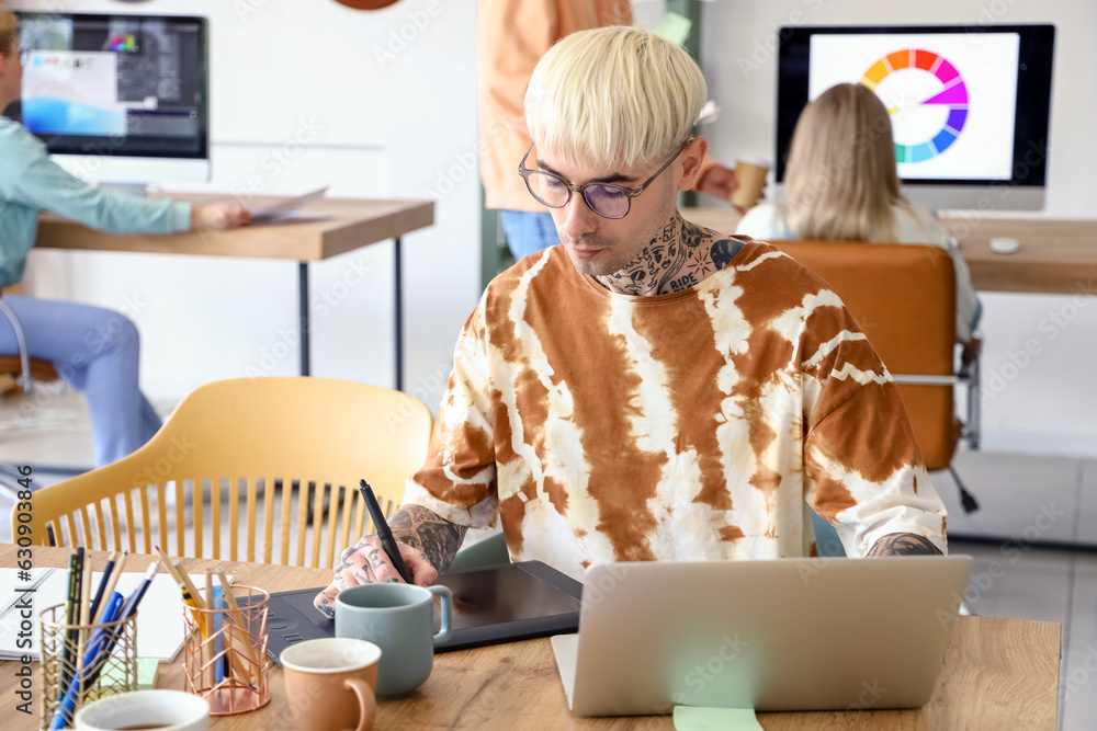 Male graphic designer working with tablet at table in office