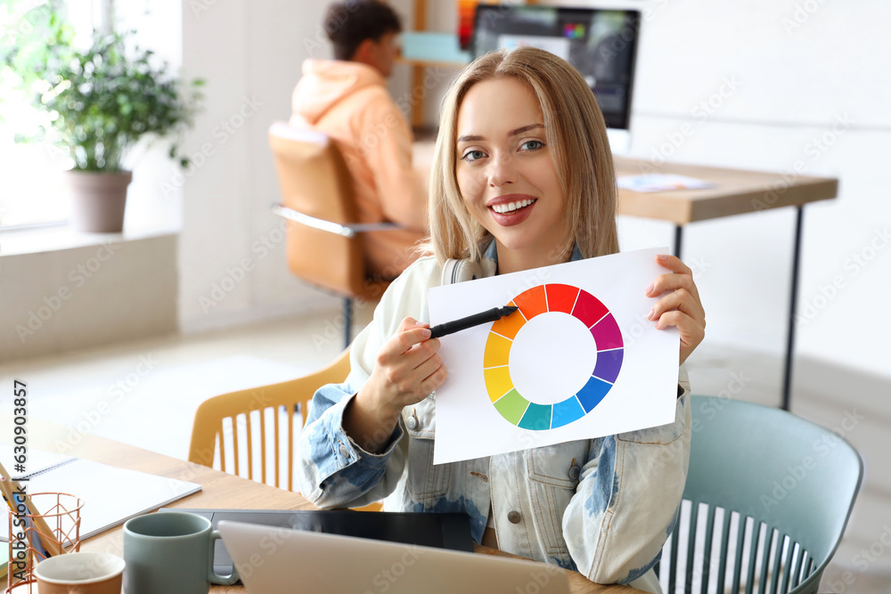 Female graphic designer working with color palette at table in office