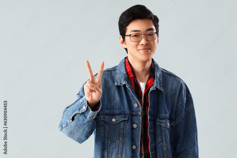 Young Asian man showing two fingers on light background