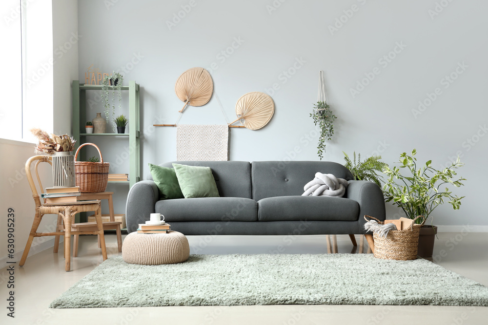 Interior of light living room with sofa, wicker basket and houseplants