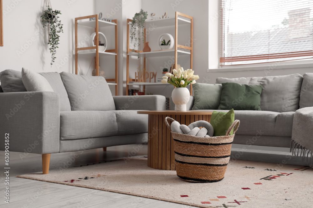 Interior of light living room with sofas, table and wicker basket