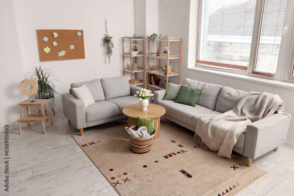 Interior of light living room with sofas, table and wicker basket