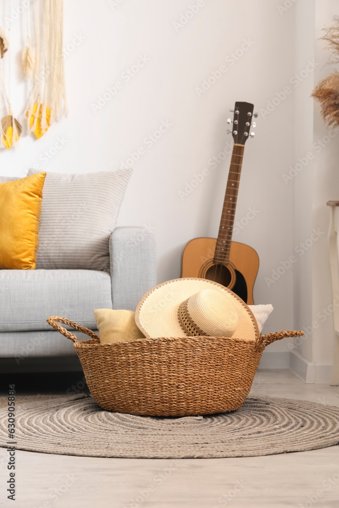 Interior of light living room with sofa, wicker basket and guitar