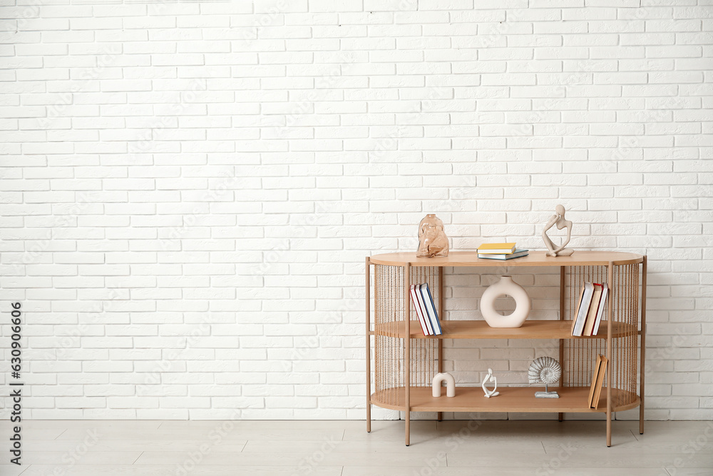 Bookshelf with decor near white brick wall in room