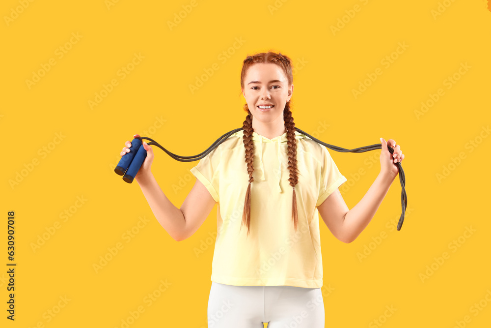 Sporty young woman with skipping rope on yellow background