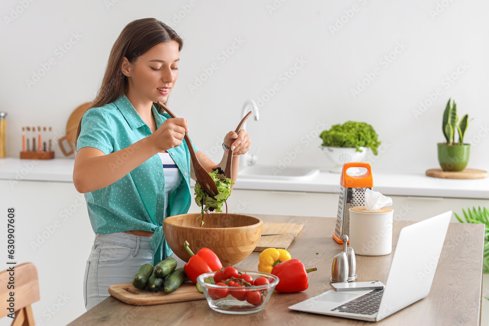 Young woman preparing vegetable salad in kitchen