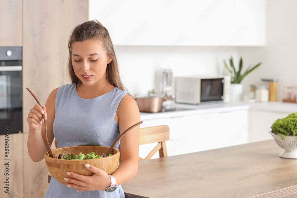 Young woman preparing vegetable salad in kitchen