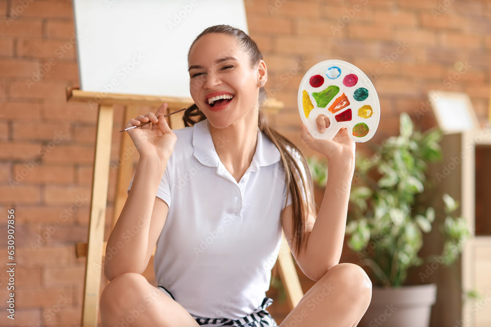 Young woman with paint palette resting on her day off at home