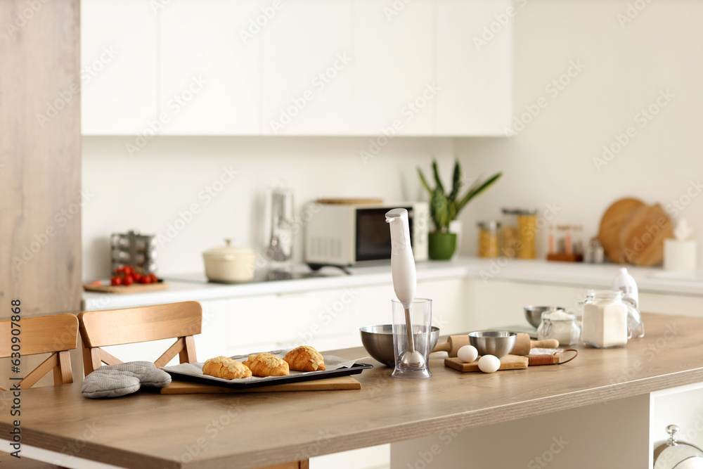 Baking tray with fresh croissants on table in kitchen