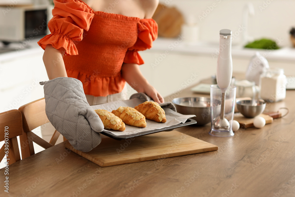 Young woman with baked croissants in kitchen, closeup