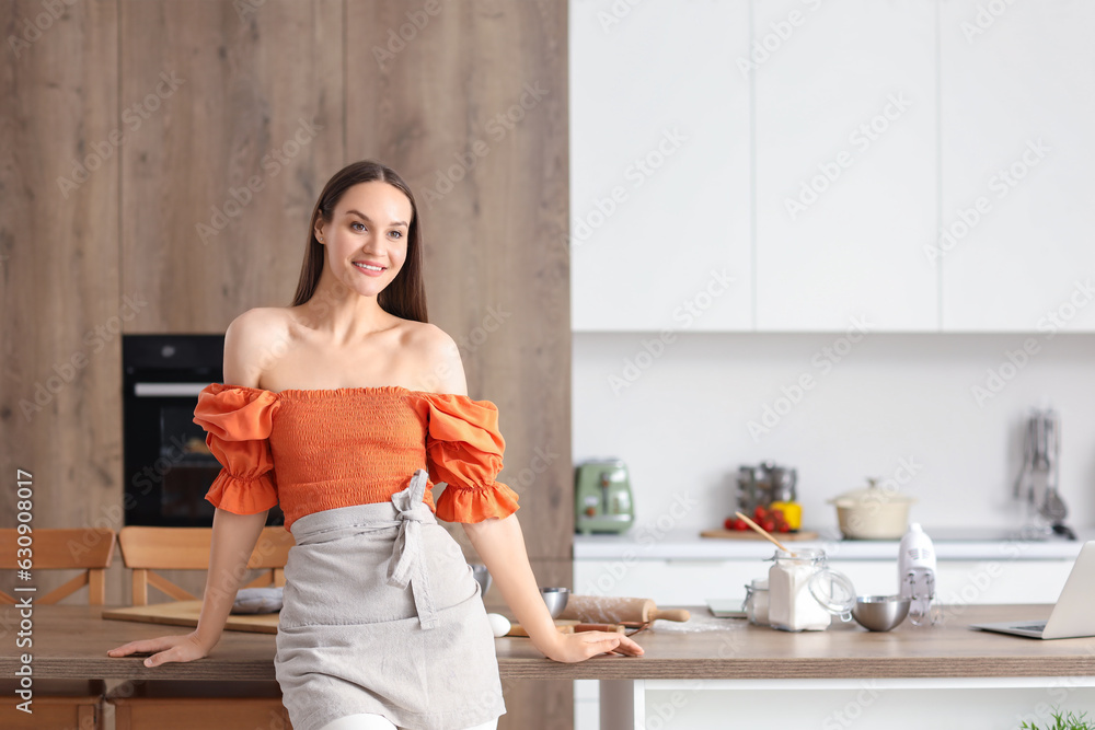 Young woman preparing dough in kitchen