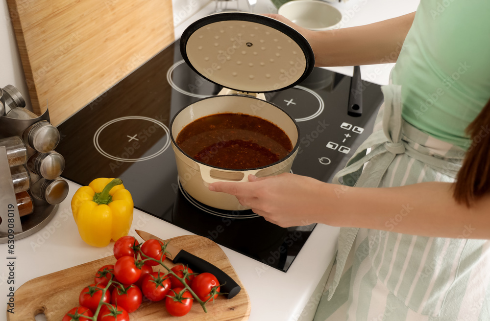 Young woman making soup in kitchen, closeup