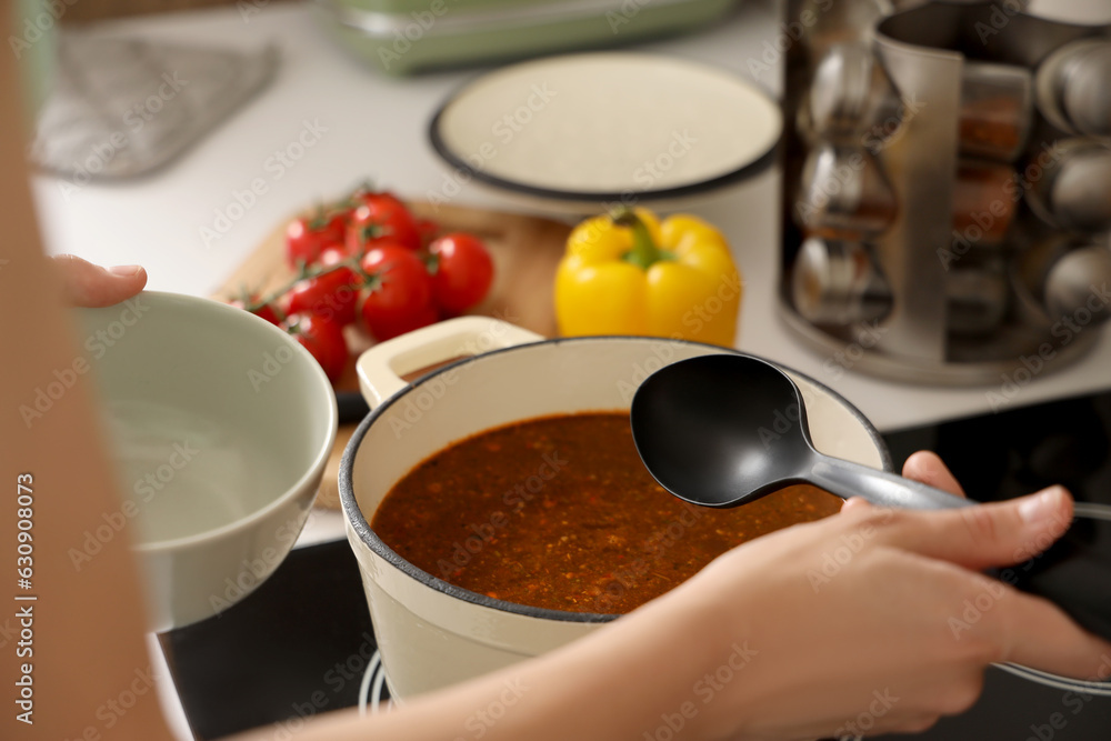 Young woman making soup in kitchen, closeup