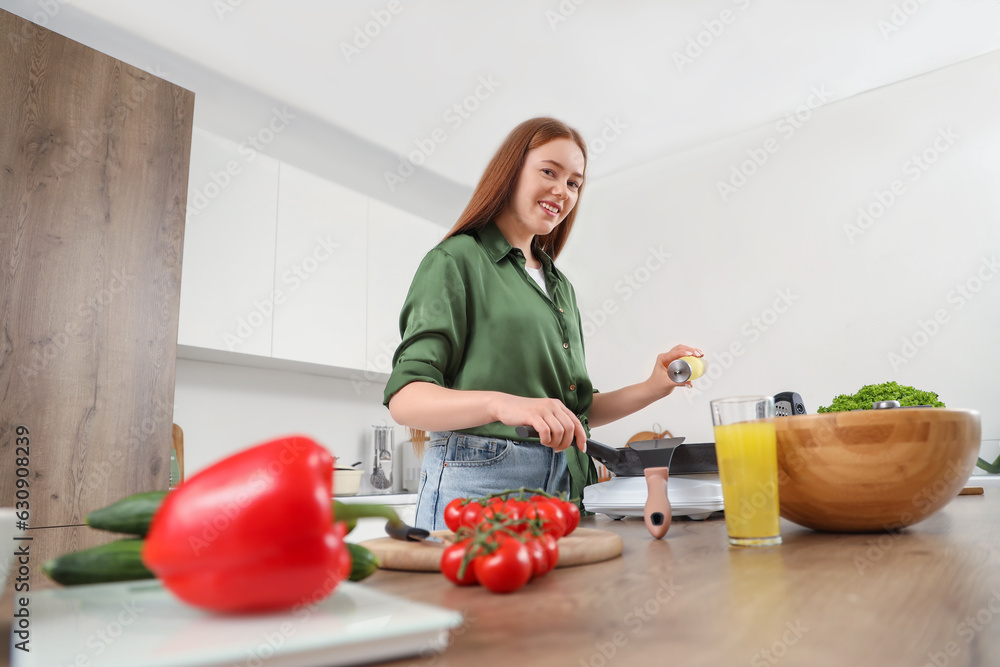 Young woman with oil frying vegetables in kitchen