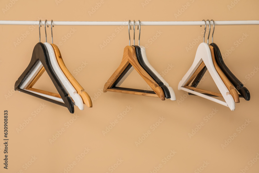 Rack with wooden clothes hangers on beige background