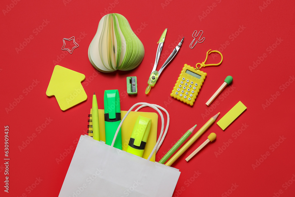 Composition with paper bag and different stationery on red background