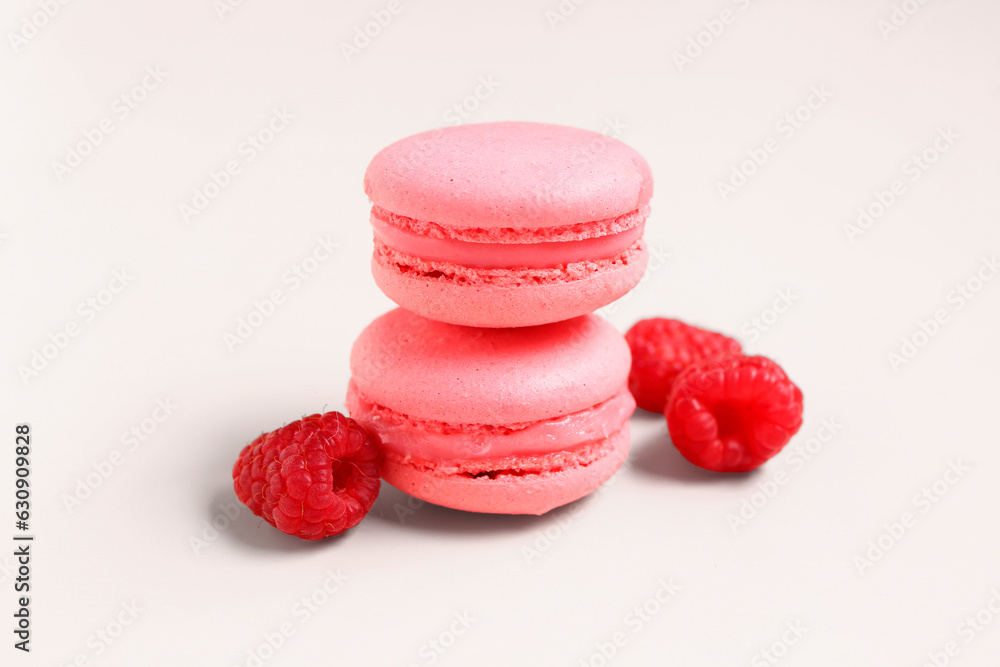 Tasty sweet macaroons and raspberries on pink background