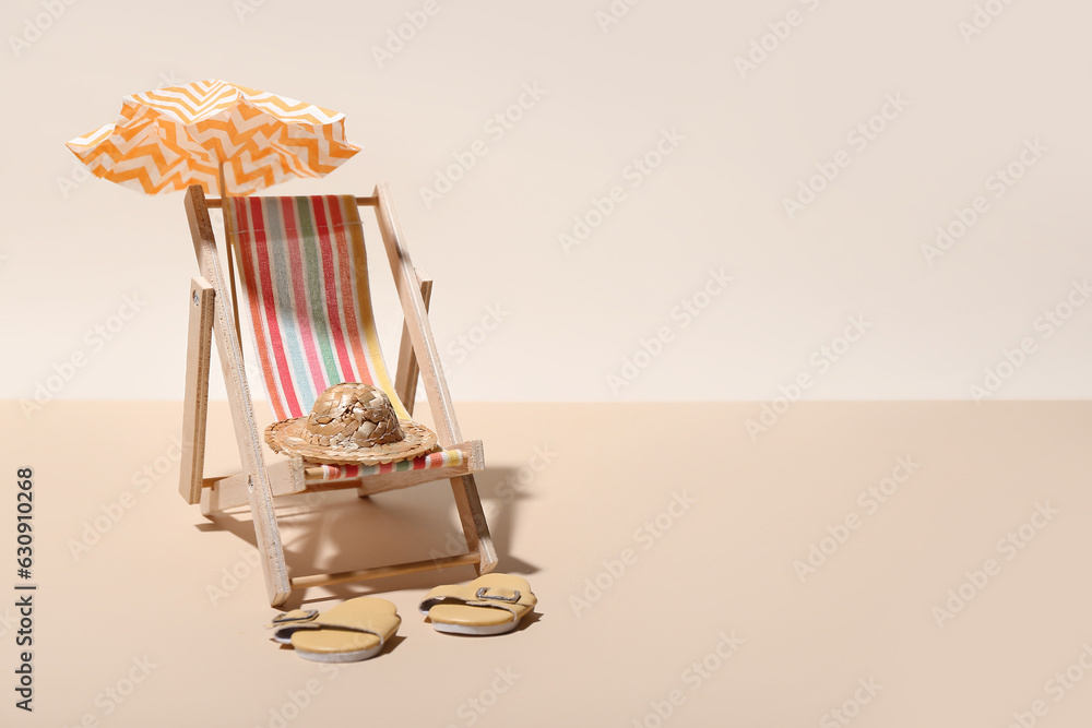 Creative summer composition with mini umbrella, deckchair and beach accessories on color background