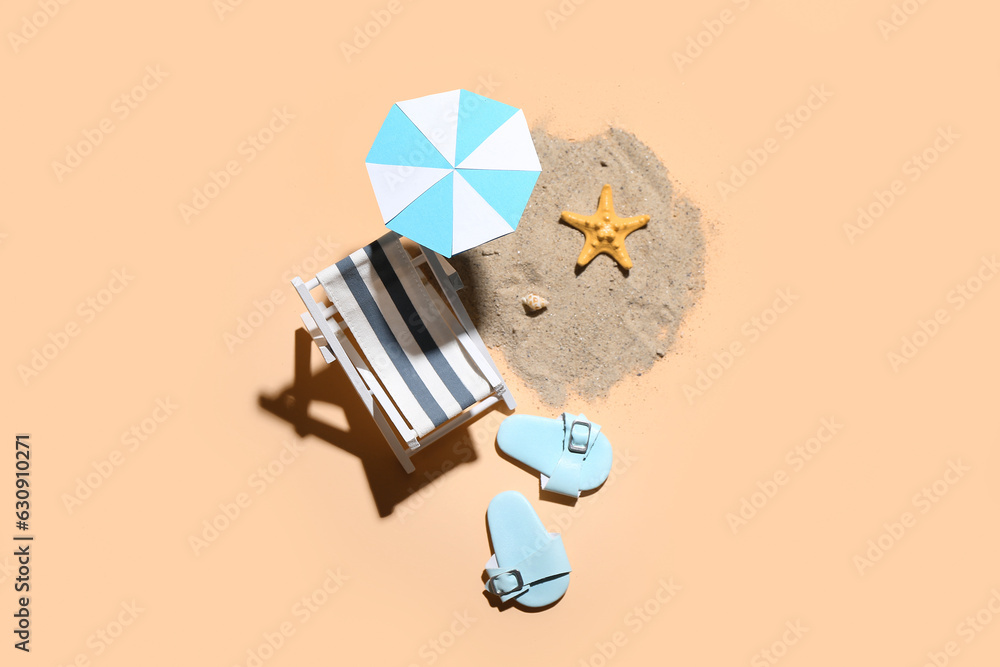 Creative summer composition with mini umbrella, deckchair and beach accessories on beige background