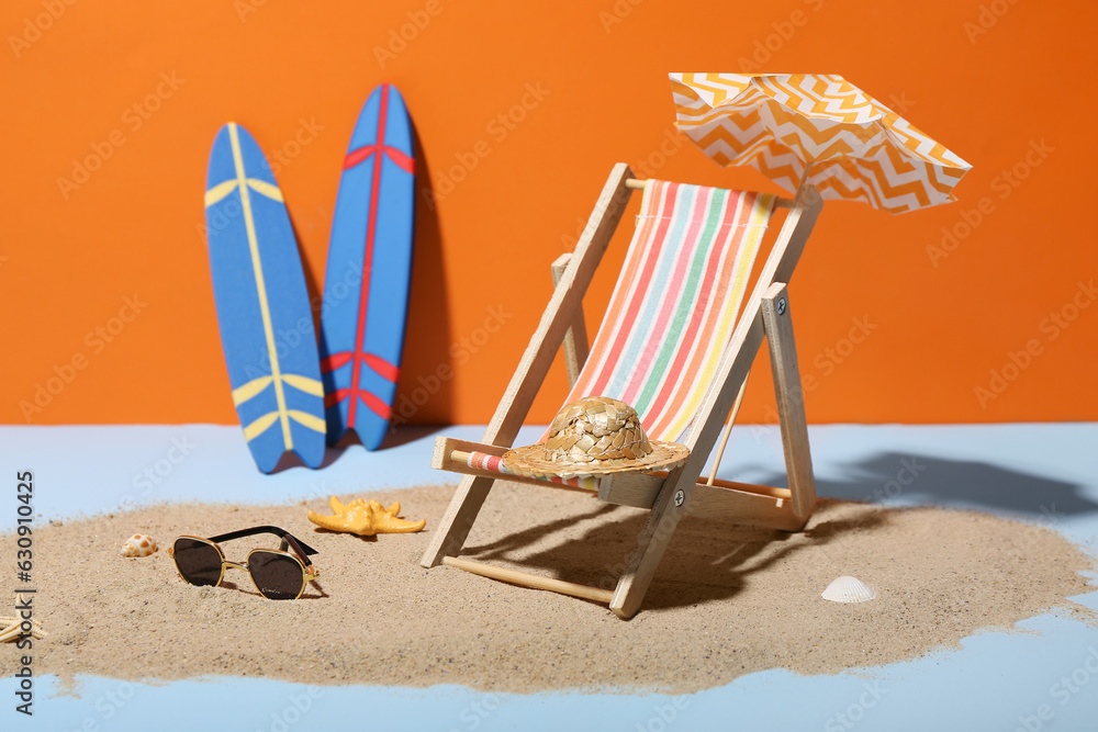 Creative summer composition with mini umbrella, deckchair and beach accessories on color background