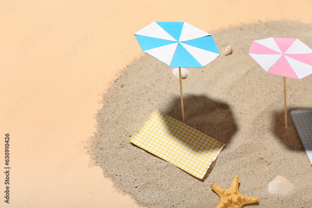 Creative summer composition with mini umbrellas, beach accessories and sand on beige background