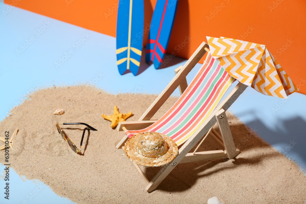 Creative summer composition with mini umbrella, deckchair and beach accessories on color background