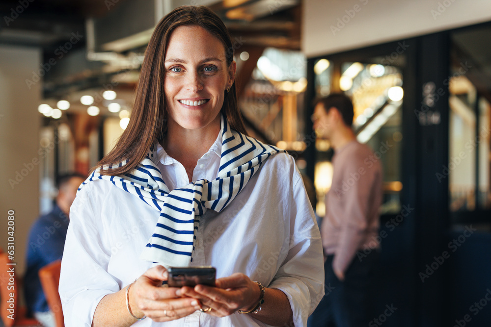 Caucasian business woman holding a cellphone in an office