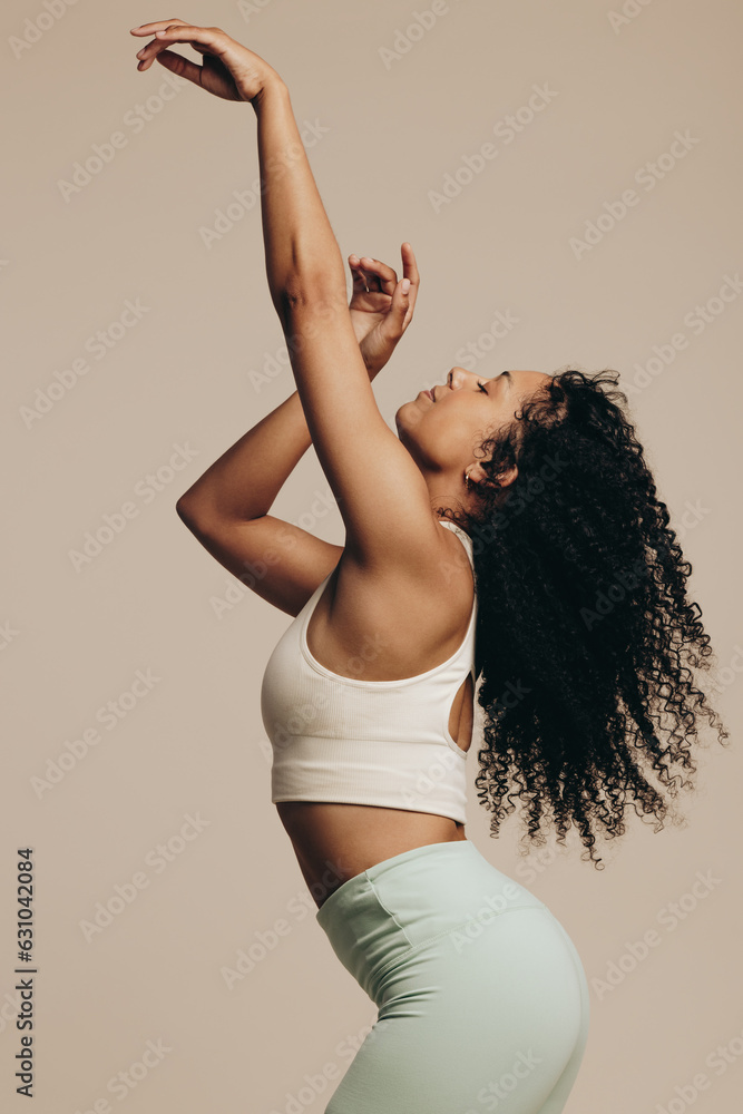 Fit young woman doing an expressive dance move in fitness clothing