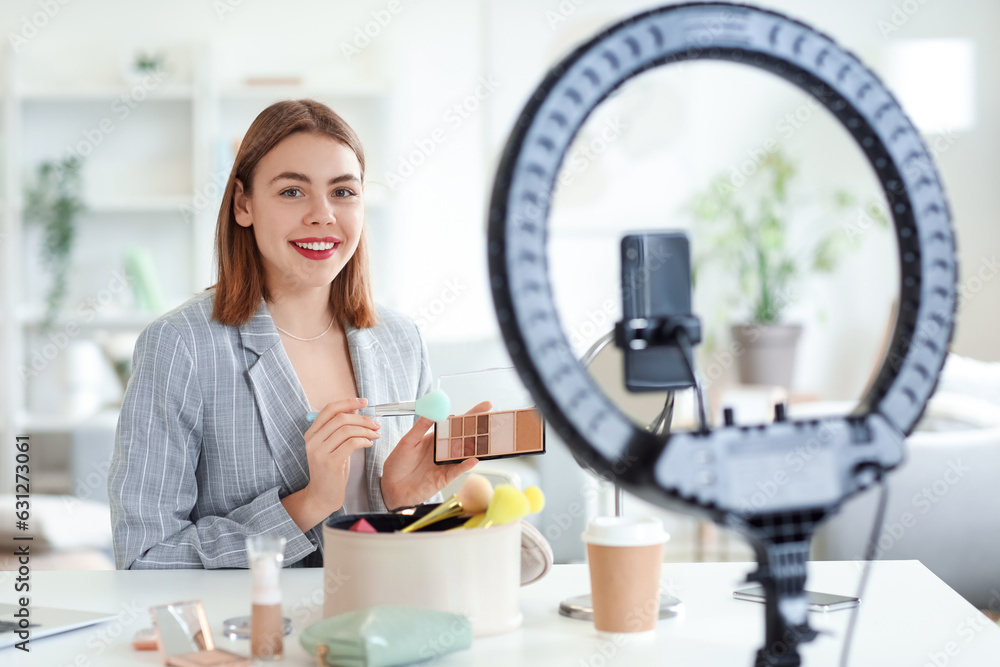 Female beauty blogger with eyeshadows recording video at home