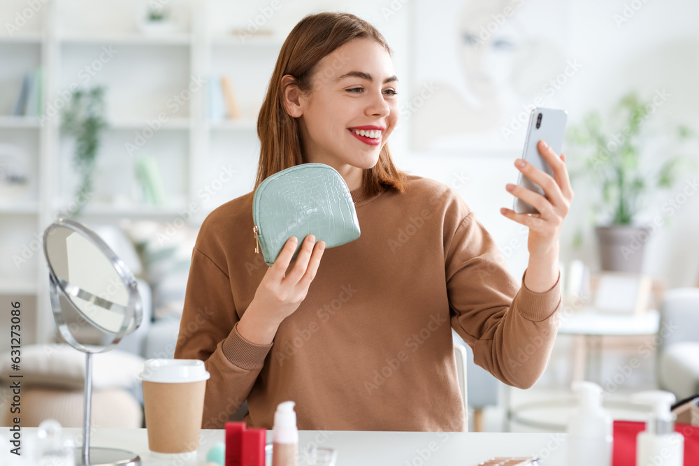 Young woman with cosmetic bag and mobile phone at home