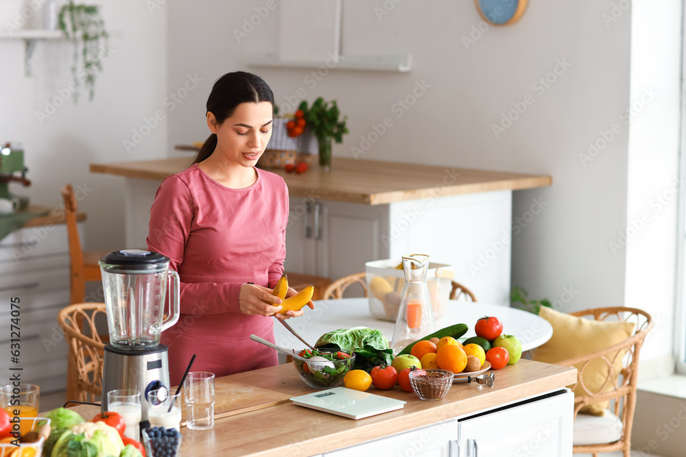 Sporty young woman with bananas in kitchen