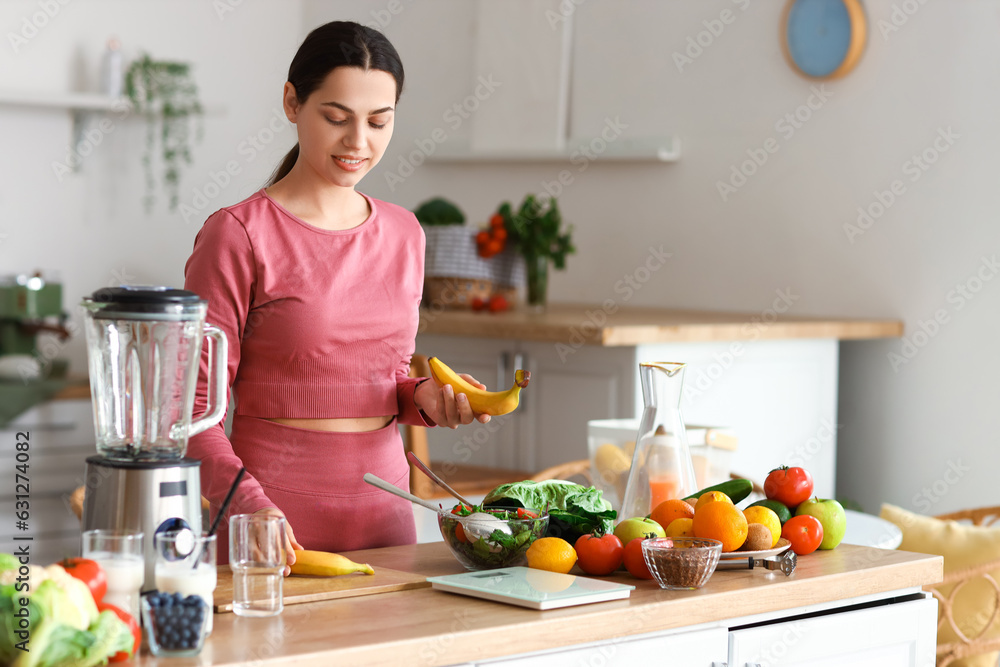 Sporty young woman with bananas in kitchen