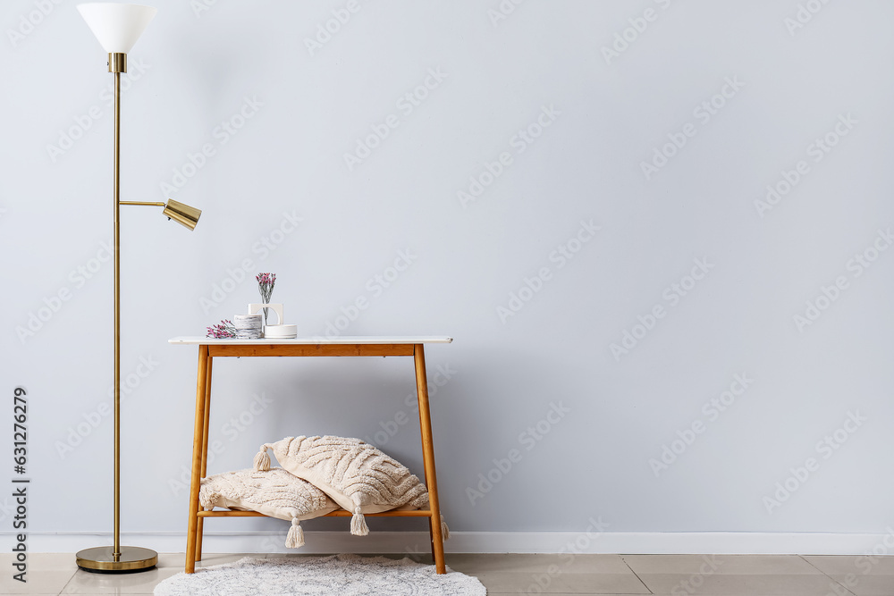 Interior of light room with lamp, pillows and flowers, candles on table