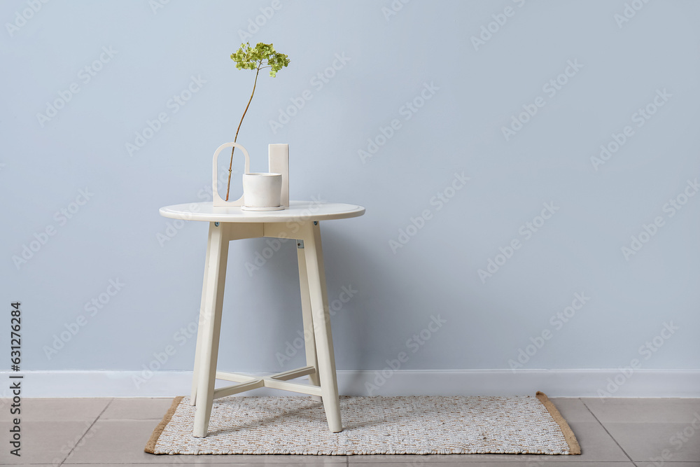 Hydrangea flowers and candle on table near light wall in room