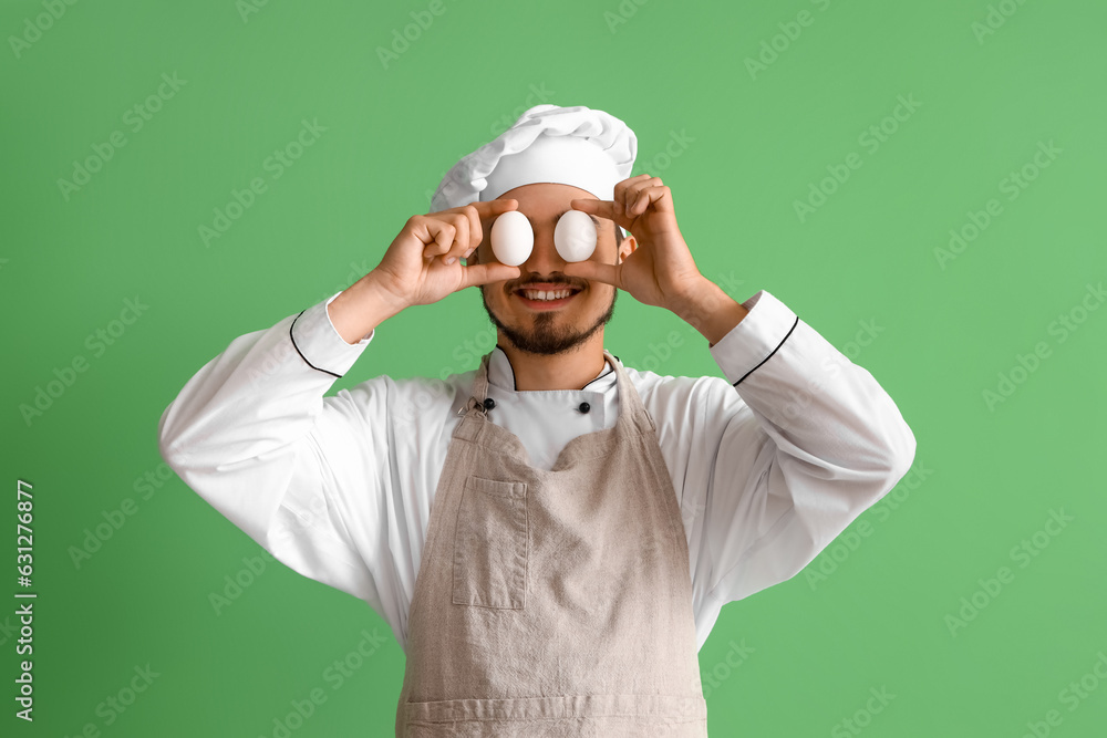 Male chef with eggs on green background