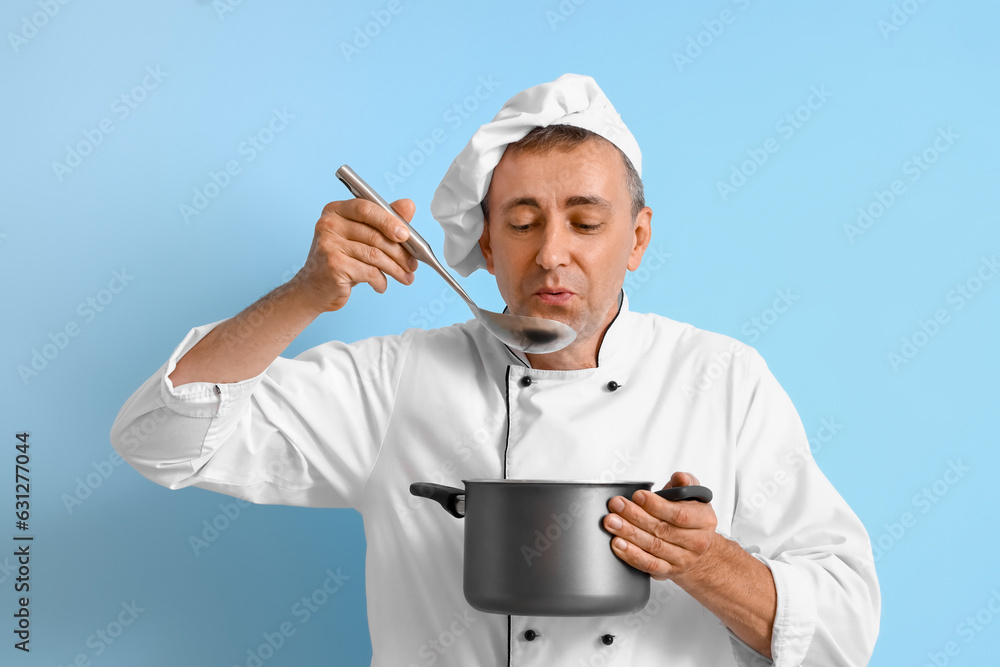 Mature chef with ladle and cooking pot on blue background