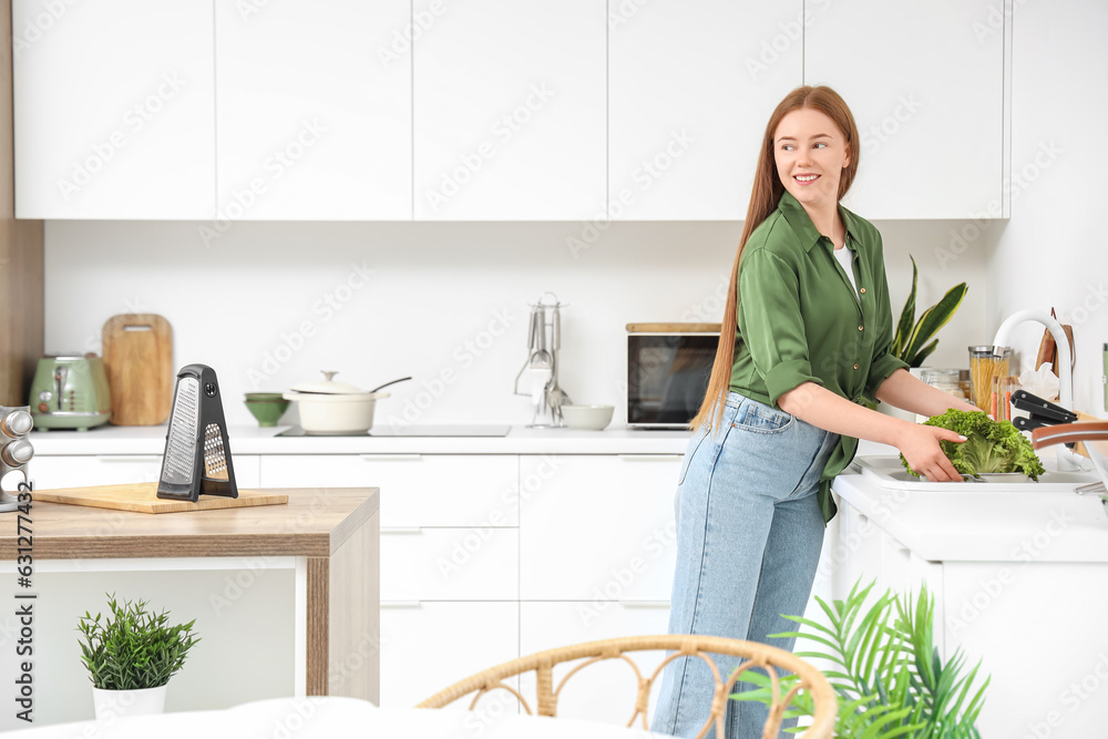 Young woman washing lettuce in sink at home