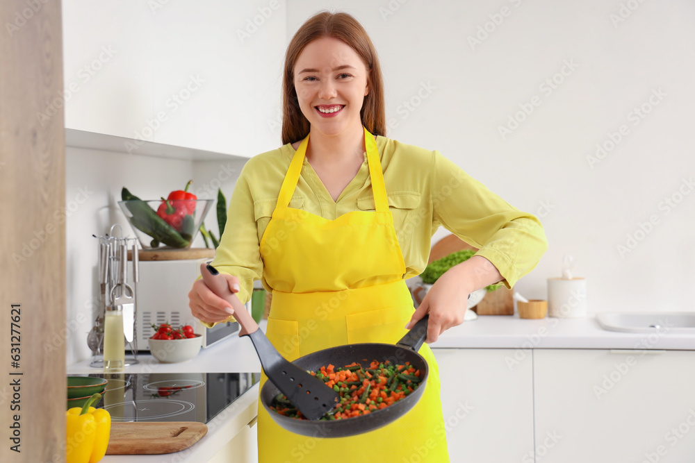 Young woman with fried vegetables in kitchen