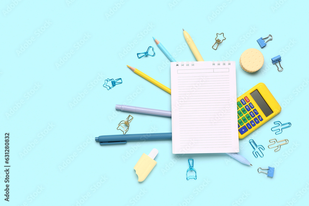 Notebook with different stationery supplies on blue background