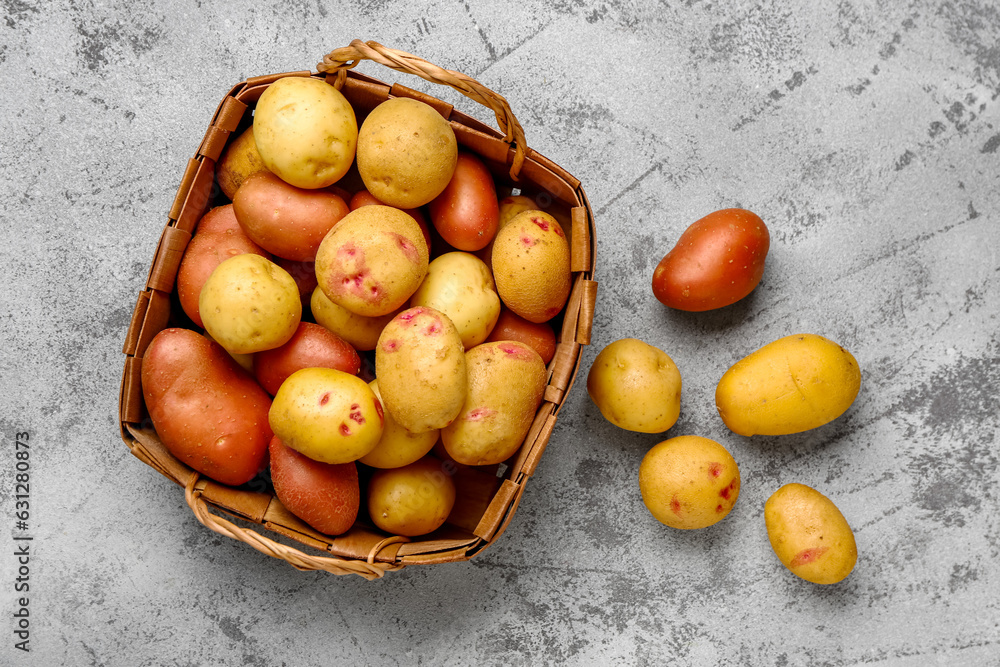 Wicker basket with fresh raw potatoes on blue background